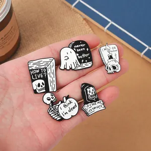 Gros plan détaillé de cinq broches en émail noir et blanc dans une paume pour voir la taille