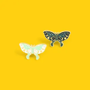 Macro detail of enamel moth pins with moon phase patterns and golden metal edges