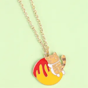 Detail of creative golden necklace with cute orange cat and red enamel pendant charm