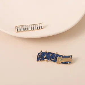 Elegantes pines de esmalte con teclado de piano y nota musical con un gato dorado