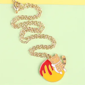 Detailed close-up of a cartoon orange cat pendant on a vibrant red and yellow ball with gold chain