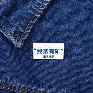 Detail of rectangular mineral water bottle pin attached to a blue denim jacket pocket
