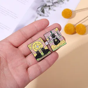 Handheld view of black cat tarot enamel pins showing Wheel of Fortune and Justice designs