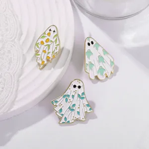 Gros plan de trois broches fantômes mignons en émail avec fleurs et bordures en alliage