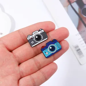 Dettaglio di due spille vintage a forma di macchina fotografica in smalto nero e blu