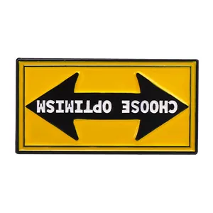 Detail of yellow enamel pin with a black arrow and Choose Optimism text design