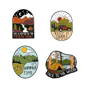 Detail view of four enamel camping pins featuring mountains, tents and retro forest designs