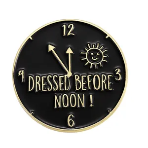 Detailansicht der schwarzen Emaille-Brosche mit goldenem Rand und DRESSED BEFORE NOON Text