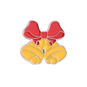 Detail of Christmas enamel brooch featuring a red bow and golden bells with silver edges