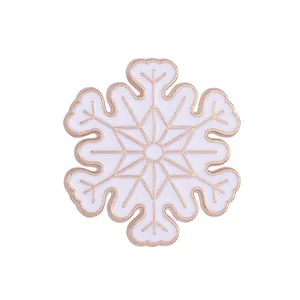 Detail showing an elegant white and gold snowflake enamel brooch with geometric symmetry