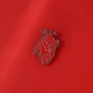 Macro detail of red anatomical heart brooch with black enamel aorta and artery lettering