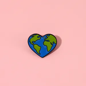 Detailed view of heart-shaped earth enamel pin with blue oceans on pink background