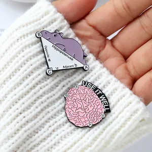 Detail of funny Hippo and Brain enamel pins on white knitted fabric with cute animal designs
