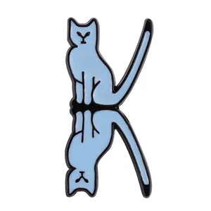 Detail of blue enamel cat pin in K-letter shape with black metal outlines on white background