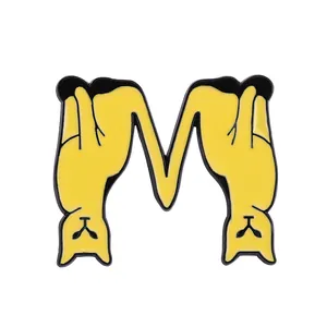 Macro detail of yellow cat letter M enamel pin made of alloy with drip oil technique