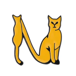 Close-up of a yellow enamel cat pin in the shape of letter N with black outlines