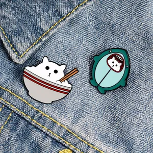 Détail de broches en émail mignonnes avec motifs de chats sur un tissu en jean bleu