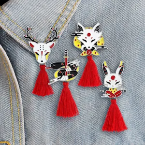 Detail van emaille pins in Japanse stijl met vos- en konijnontwerpen en rode kwastjes