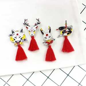 Detailopname van een vierdelige set Japanse emaille pinnen met rode kwastjes en dieren