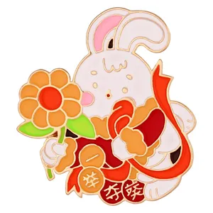 Détail de la broche lapin en émail blanc avec fleur orange et rubans festifs