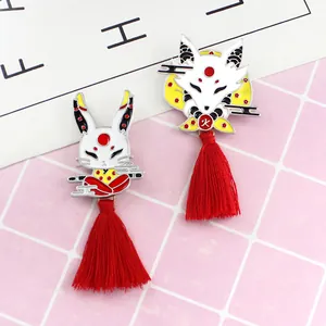 Detail van Japanse konijn en vos emaille broches met lange rode zijden kwastjes