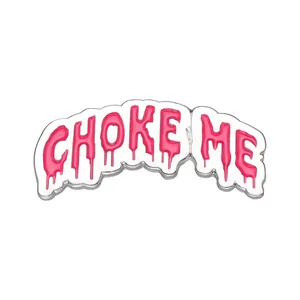 Dettaglio macro della spilla smaltata con scritta 'CHOKE ME' rosa e bordi argentati