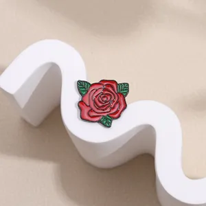 Elegant red enamel rose brooch with green leaves on white geometric display stand