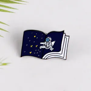 Spilla creativa in smalto con astronauta e libro aperto tema spazio blu profondo