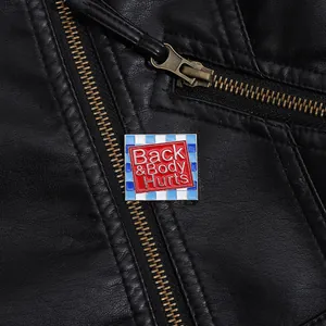 Close-up of enamel pin with Back & Body Hurts text on black leather jacket