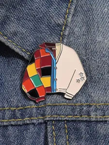 Detailed view of enamel sweater brooch pinned on denim jacket with patchwork pattern
