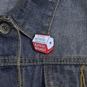 Close-up of a creative cooler-shaped enamel pin attached to a blue denim jacket lapel