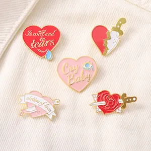 Detailed view of five pink and red enamel heart brooches on white striped fabric