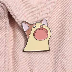 Détail du pin's émaillé Pop Cat avec bouche ouverte sur un tissu en denim rose