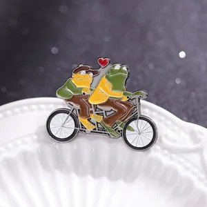 Broche en émail grenouilles sur un vélo tandem avec cœur sur une assiette en céramique