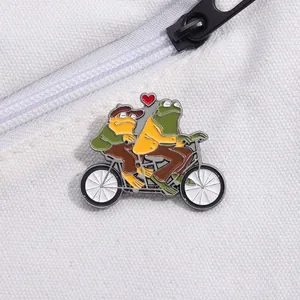 Détail de pins en émail montrant deux grenouilles sur un tandem sur tissu en toile