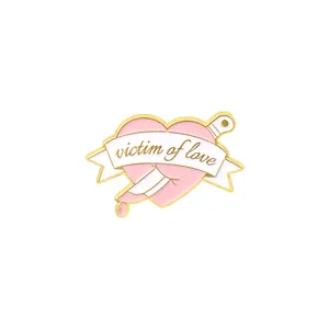 Detail of Victim of Love heart pin with dagger and pink enamel finish in gold plating