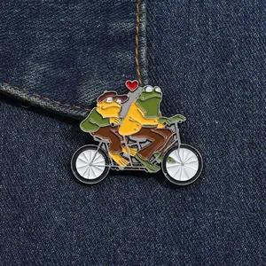 Broche en émail représentant des grenouilles en tandem avec un cœur sur du denim