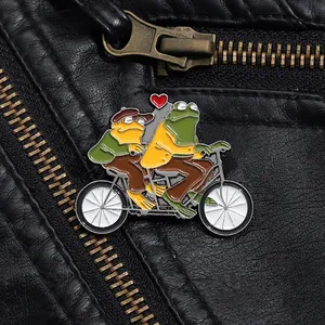 Détail du pin's émaillé montrant deux grenouilles sur un tandem sur une veste en cuir