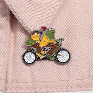 Broche en émail représentant les personnages Grenouille et Crapaud sur un tandem