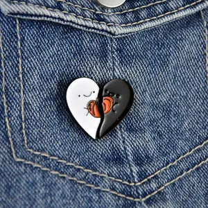 Detail of black and white heart enamel pin with red accent on denim jacket pocket