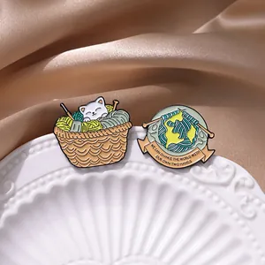 Gros plan détaillé de broches émaillées chat et pelote sur fond satiné élégant