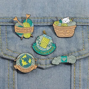 Détail de 5 broches en émail sur le thème du tricot sur une poche de veste en jean