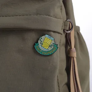 Détail de l'épingle émaillée 'KNIT HAPPENS' avec bobine de fil sur un sac à dos vert