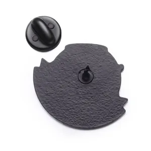 Détail de l'arrière d'un badge en métal noir mat avec texture sablée et attache en caoutchouc