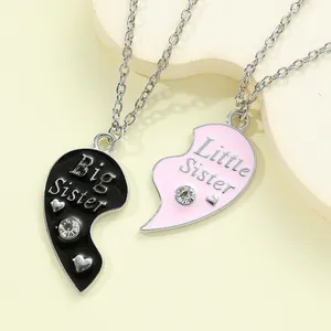 Close-up of Big Little Sister split heart pendant necklaces with pink and black enamel details