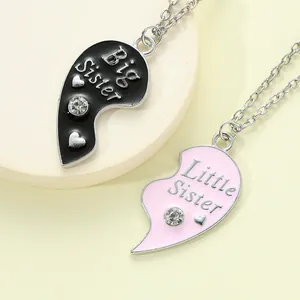 Close-up of Big Little Sister heart pendant necklaces with pink and black enamel detail