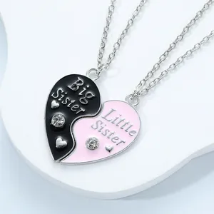 Close-up of black and pink heart puzzle necklaces with Big and Little Sister engraving