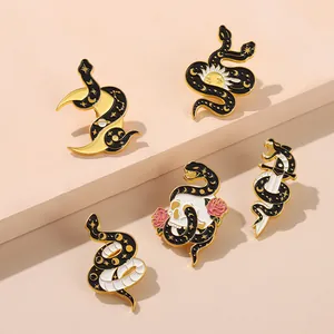 Gothic gold alloy snake enamel pins set with moon, sun and skull motifs on pink background