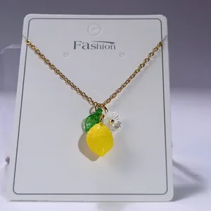 Detail of yellow lemon pendant necklace with green leaf and small white flower accents