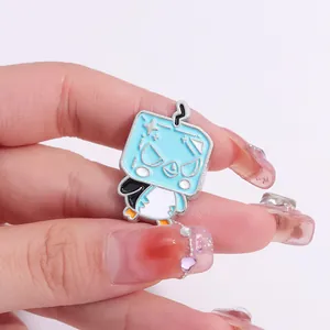 Close-up of a blue square cartoon enamel pin being held to show small size and alloy detail